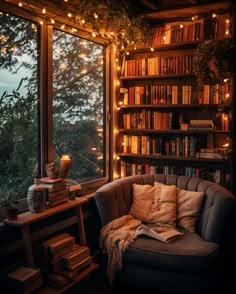 a couch sitting in front of a window filled with books and lit up by fairy lights