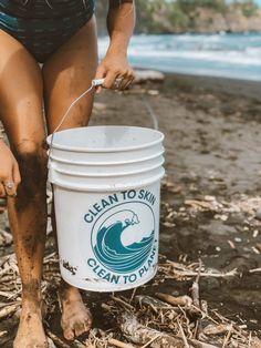 a woman in a bathing suit is holding a bucket with the ocean to sink logo on it