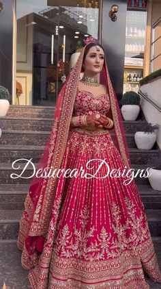 a woman in a red and gold bridal gown standing on steps with her hands behind her head