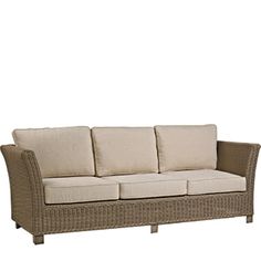 a wicker couch with four pillows on it's back and side ends, in front of a white background