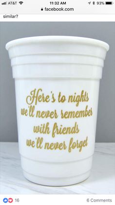 a white cup with gold writing on it sitting on a countertop next to a gray wall