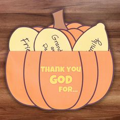 an orange pumpkin with thank you god for written on the front and side, sitting on a wooden surface