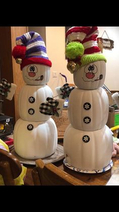 two snowmen wearing hats and scarves on top of each other in front of a table