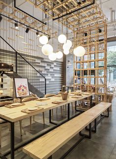 a long table with wooden benches and lights hanging from the ceiling