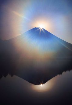 the sun shines brightly on top of a mountain as it reflects in a body of water