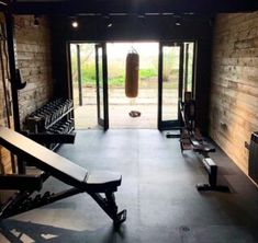 an empty gym room with benches and punching bag on the wall, in front of glass doors