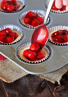 someone is dipping cherries into cupcake tins