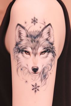 a woman's arm with a tattoo of a wolf and snowflakes on it