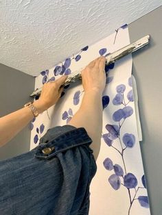 a person is using a paint roller to paint the ceiling in blue and white flowers