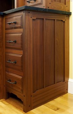 a wooden cabinet with black top and drawers