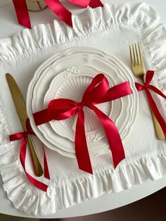 a white plate topped with a red ribbon next to a fork and knife on top of a table