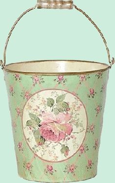 a green bucket with pink flowers on it and a metal handle hanging from the side