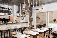 an empty restaurant with tables and chairs in front of the counter, lights hanging from the ceiling