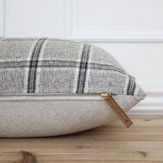 a close up of a pillow on a wooden floor with a white wall in the background