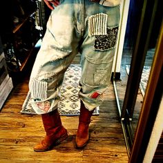 a person standing in front of a mirror wearing jeans with patches on them and brown boots