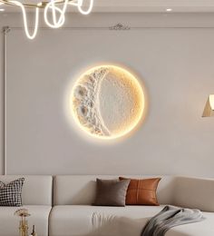 a living room with a white couch and a large moon on the wall above it