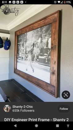 an old photo hanging on the wall above a wooden bench in front of a window