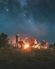 a group of people sitting around a campfire under the stars