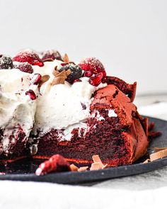 a piece of cake on a plate with whipped cream and cranberry toppings