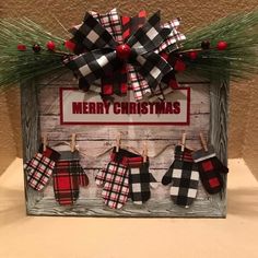 a christmas card holder with stockings hanging on clothes pins and pine needles in front of a sign that says merry christmas