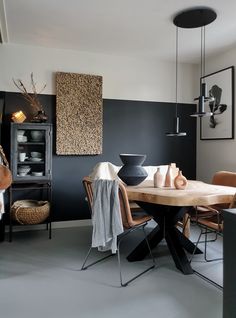 a dining room with black walls and wooden table surrounded by chairs, artwork on the wall