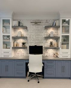 a home office with built - in shelving, desk and computer monitor on it