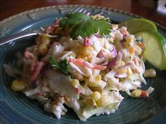 a salad with corn and cilantro on a blue plate next to a lime wedge