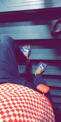 a person wearing blue and white checkered slippers sitting on a bench with their feet up