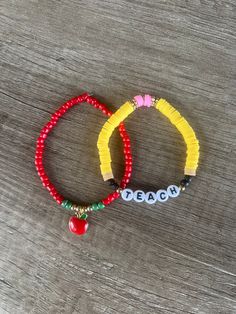 two beaded bracelets with the word beach written on them, sitting on a wooden surface