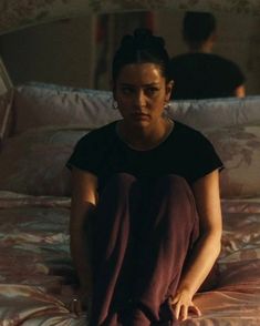 a woman sitting on top of a bed in a bedroom