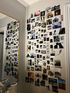 a wall with many pictures on it next to a mirror