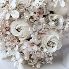 a bridal bouquet with white flowers and pearls on the bottom is adorned with swaroons