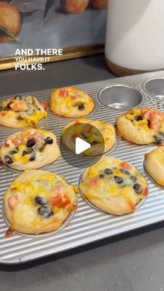 mini pizzas sitting on top of a metal pan next to a cupcake tin