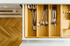 spoons and forks are stored in an open drawer