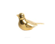 a gold bird figurine sitting on top of a white surface