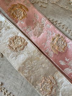 three different types of fabric with gold and pink flowers on the side, along with other material