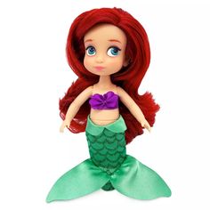 the little mermaid doll has red hair and is wearing a green dress with purple bows