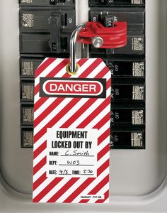 a red and white danger tag attached to an electrical outlet with black boxes in the background