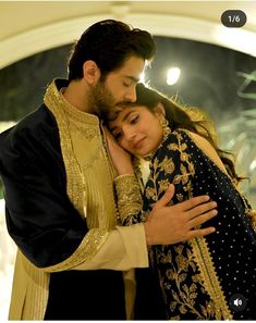 a man and woman hugging each other in front of a mirror with lights behind them