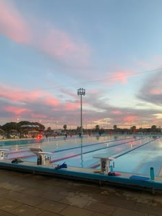 an empty swimming pool with no people in it at sunset or sunrise time, and the sun is setting