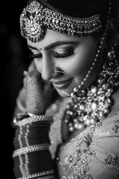 a woman in a bridal outfit with jewelry on her head and hands near her face