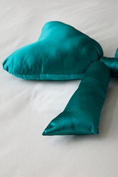 two green pillows laying on top of a white bed