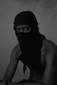 a man with a black mask on his face and wearing a scarf over his head