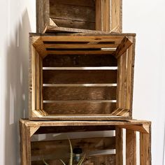 three wooden crates stacked on top of each other next to a plant in a vase