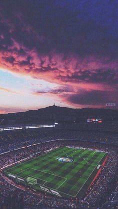 a stadium filled with lots of people watching a soccer game at sunset or dawn in the evening