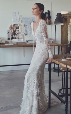 a woman in a white wedding dress leaning on a table with her back to the camera