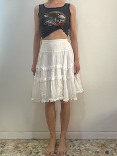 Beautiful 1970s white cotton Kenzo peasant skirt.  The most beautiful part of this skirt is the fine cotton - holds a wonderful shape while being at the same time so light and floaty.  Three tiers of mini ruffles.   Fully lined with more ruffles.  Plastic zipper at the side with one button at the waist.  Label Kenzo Paris, size 40, 100% cotton. Hand wash cool, drip dry. Very good vintage condition with no fabric or sewing flaws.  Measurements Waist 70cm/ 27.5inches Hips - gathers so full Waist to hem 59cm/ 23.5inches Models measurements Shoulders 42cm/ 16.5inches Chest 84cm/ 33inches Waist 66cm/ 26inches Hips 92cm/ 36inches Height 175cm/ 5'9'' Vintage White Skirt With Attached Cancan, Summer Cotton Skirt With Attached Cancan, Vintage Ruffled Skirt Petticoat, Vintage Tiered Petticoat With Lined Skirt, Vintage Ruffled Spring Petticoat, Vintage Spring Petticoat With Ruffled Skirt, Vintage Ruffled Petticoat For Spring, White Ruffled Petticoat With Flowy Fit, Vintage Petticoat With Attached Cancan For Summer