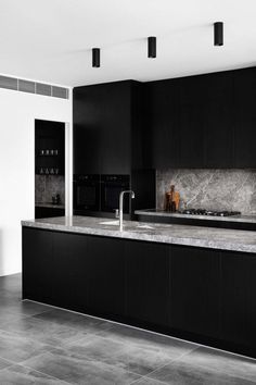 a kitchen with black cabinets and marble counter tops