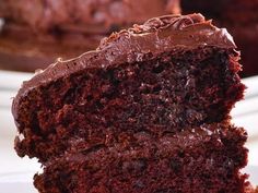 a piece of chocolate cake on a plate with one slice taken from it and the rest of the cake in the background