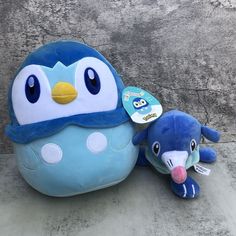 two stuffed animals sitting next to each other on the ground in front of a wall